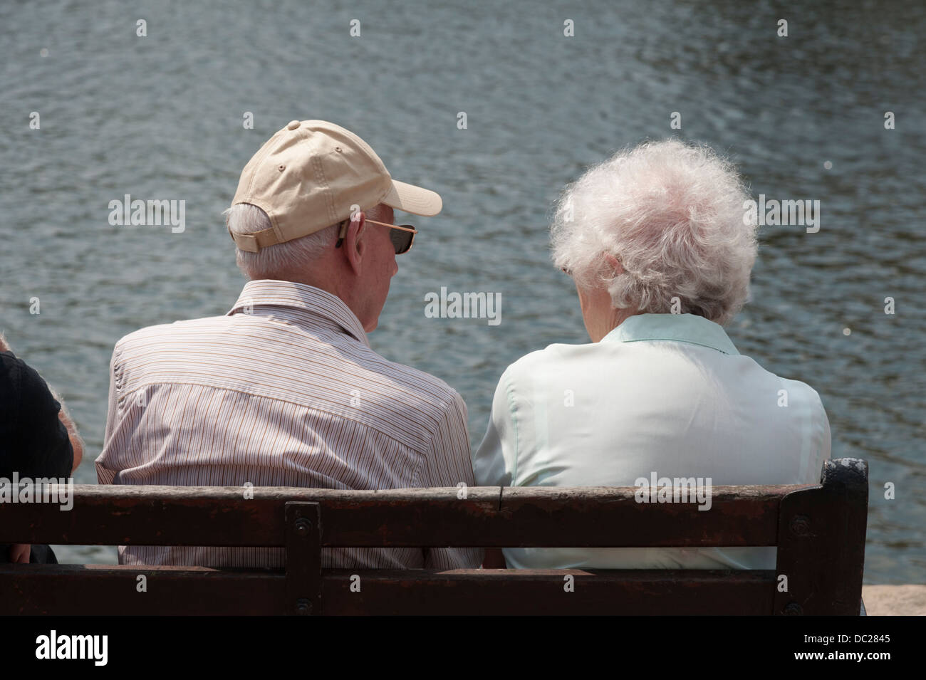 Rückansicht des älteren Menschen sitzen auf einer Bank mit Blick auf einen Fluss an einem Sommertag Stockfoto