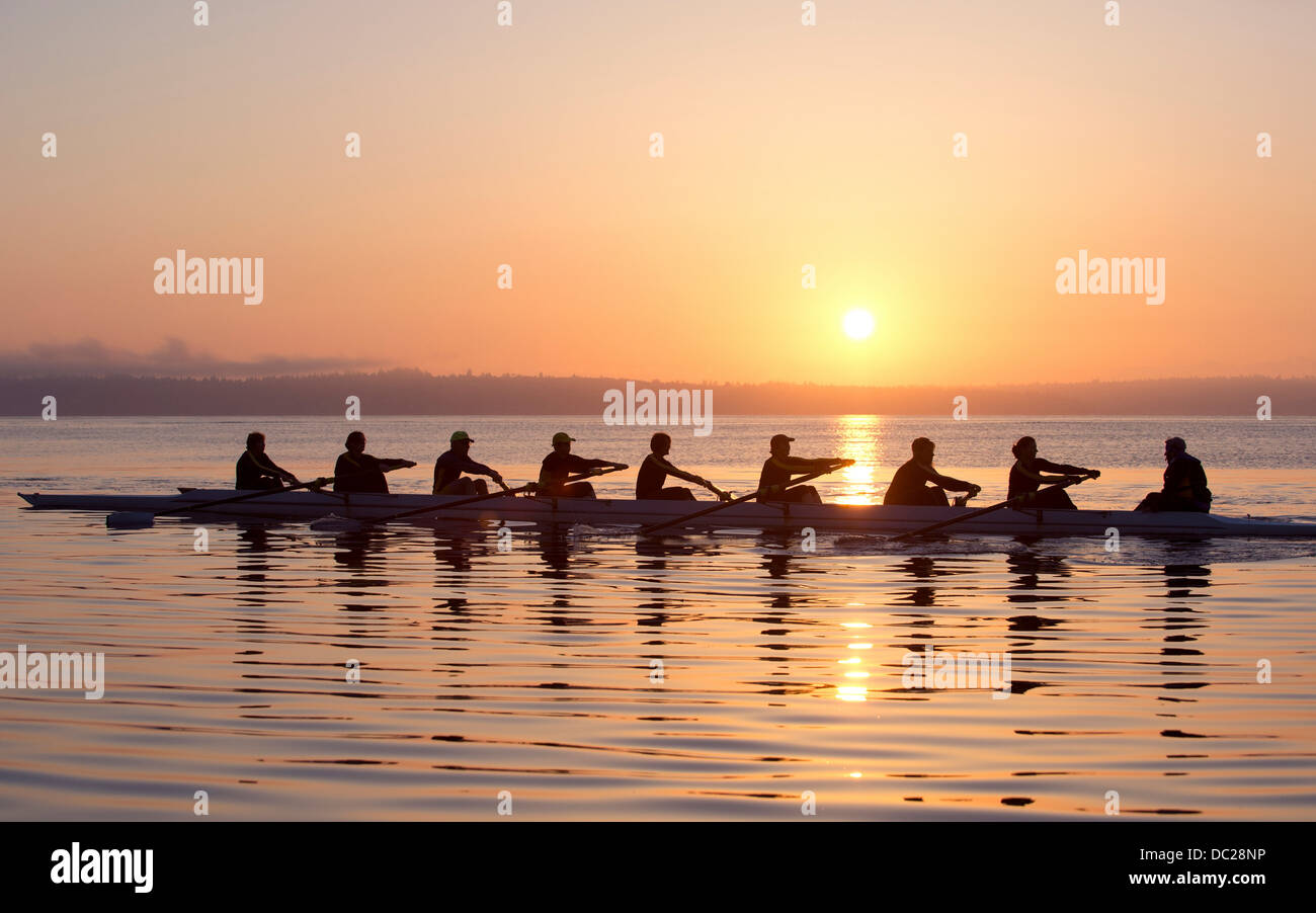 Neun Menschen bei Sonnenuntergang Rudern Stockfoto