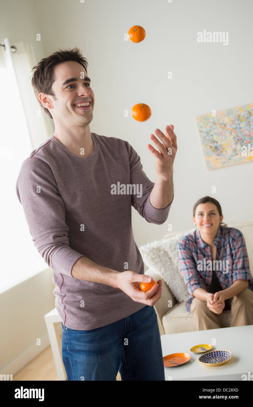 Mann jonglieren Orangen, Frau beobachten Stockfoto