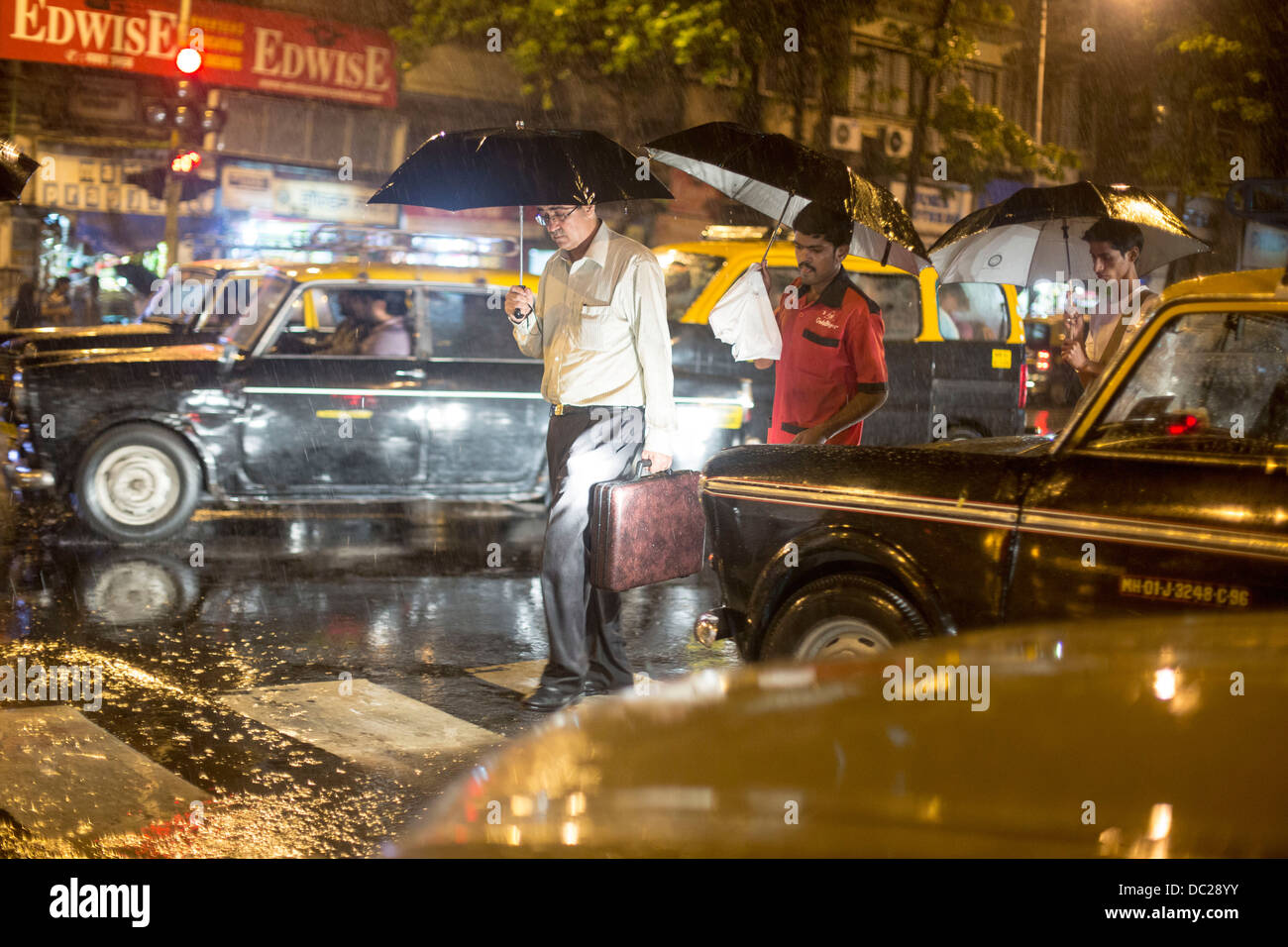 die Taxis in Regen mit Sonnenschirmen Monsun vorbeigehen Stockfoto