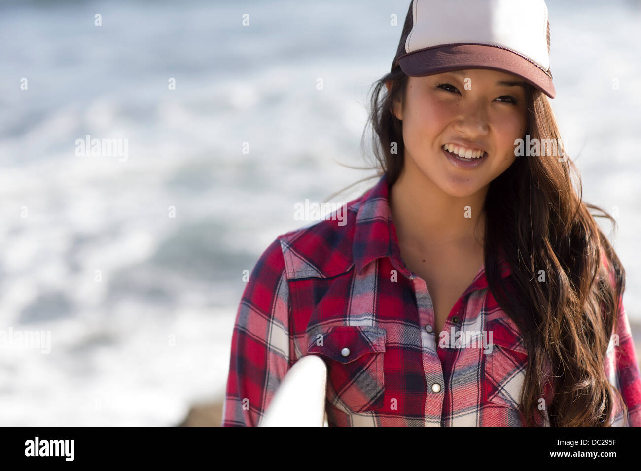 Junge Frau mit Baseballmütze mit Surfbrett Stockfoto