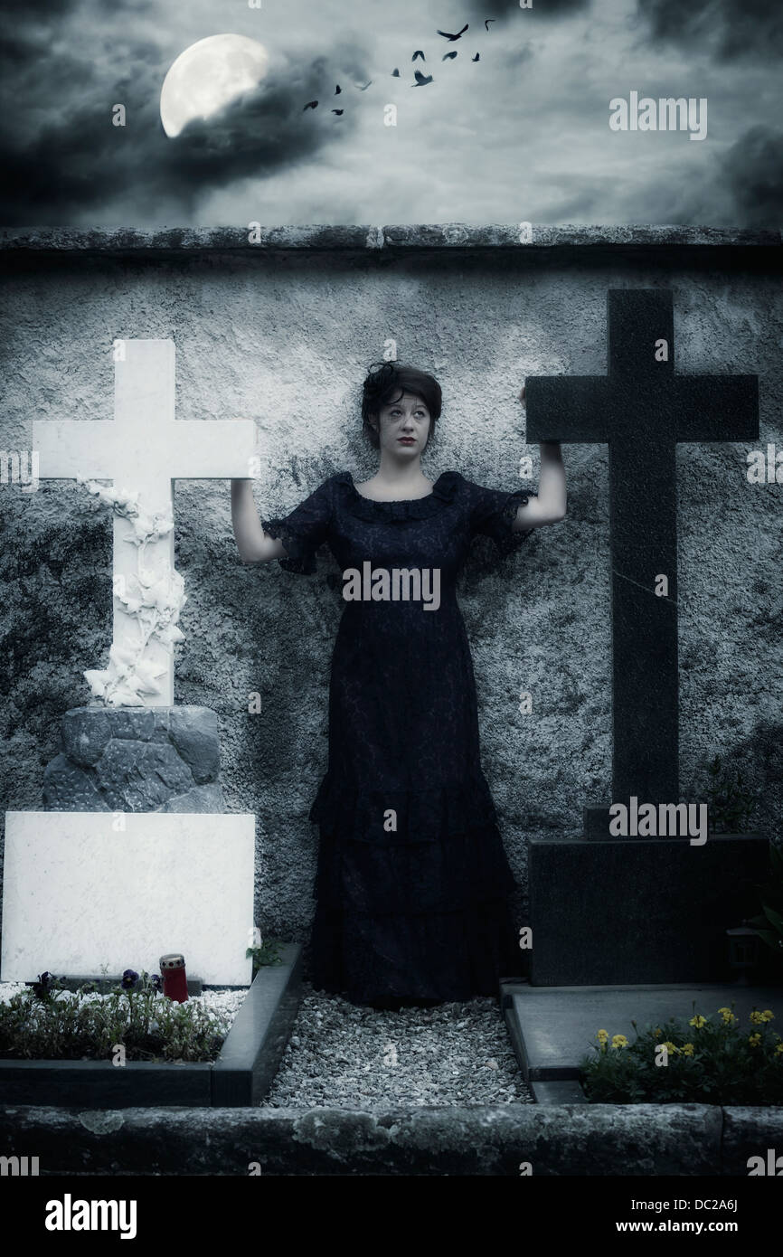eine trauernde Frau mit Schleier und dunkles Kleid auf einem Friedhof Stockfoto
