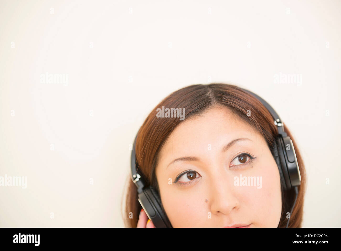 Frau trägt Kopfhörer, die auf der Suche nach oben Stockfoto