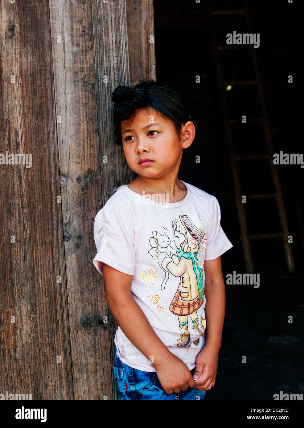ein Miao-Mädchen mit einer ethnischen Frisur Blick aus dem Fenster. Stockfoto