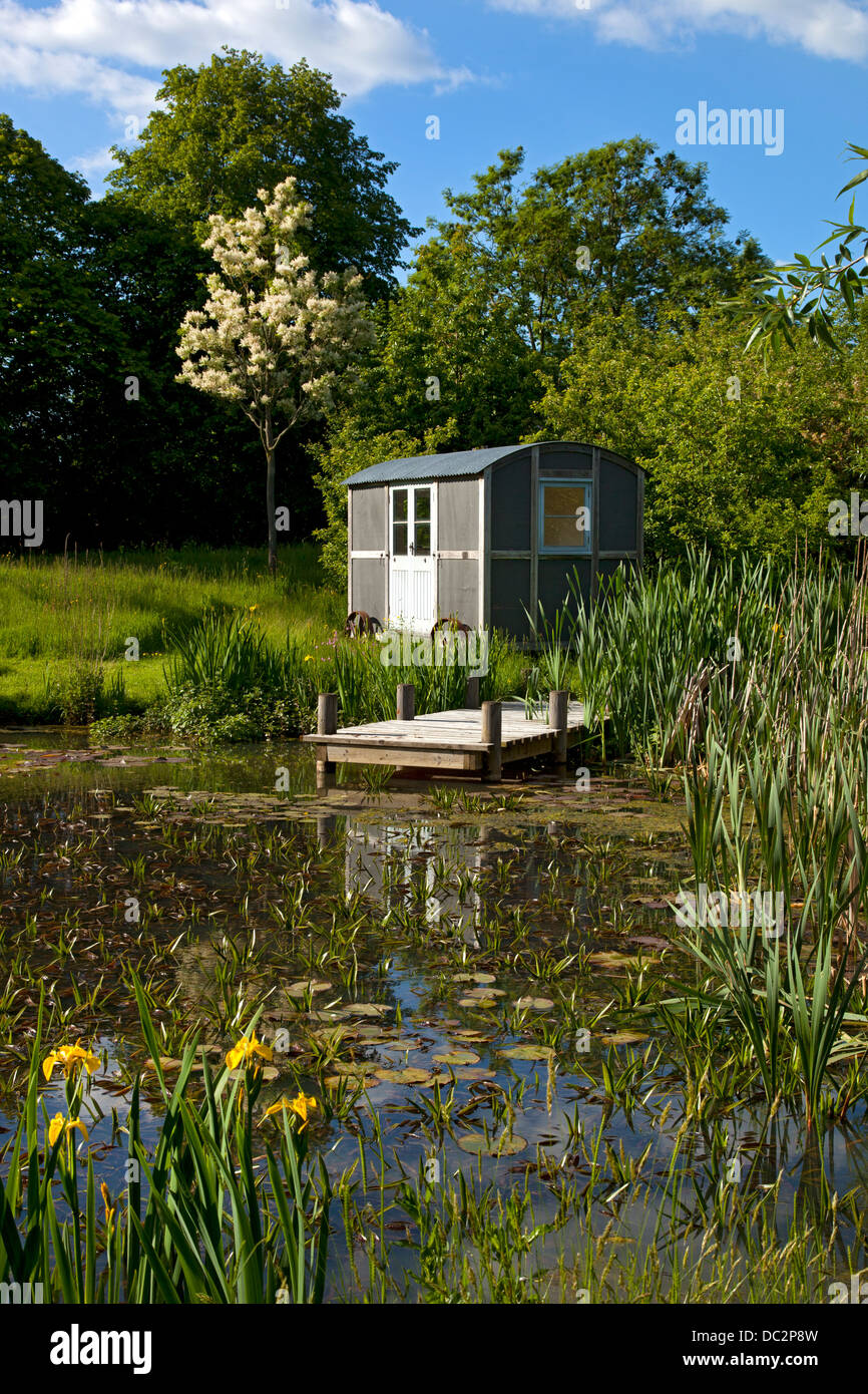 Hirten-Hütte auf Rädern im Garten am Teich, England Stockfoto