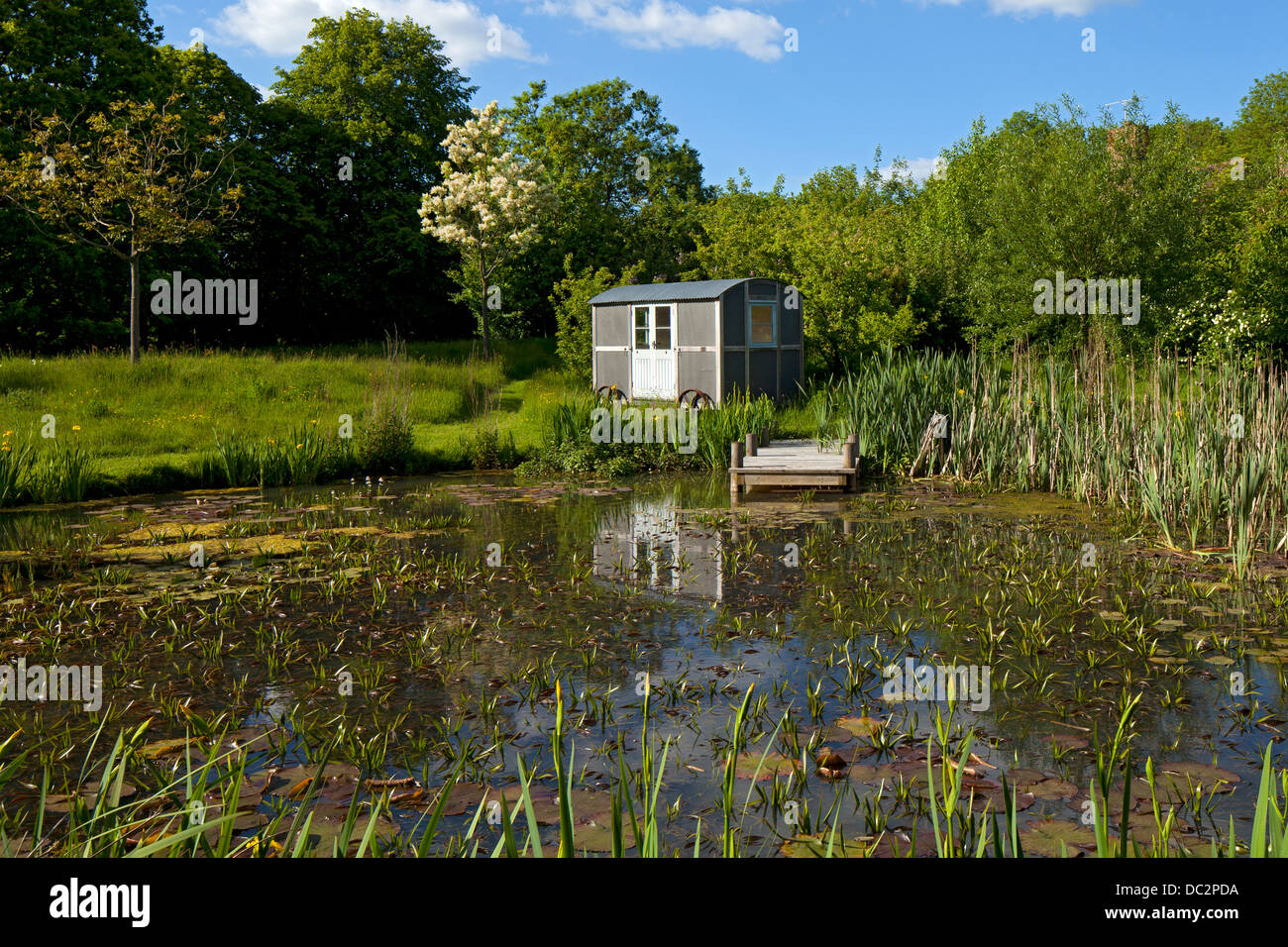 Hirten-Hütte auf Rädern im Garten am Teich, England Stockfoto