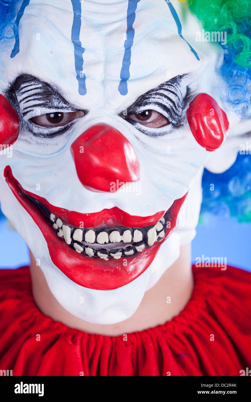 Beängstigend Clown Person in Clownsmaske auf blauem Hintergrund Studio gedreht Stockfoto