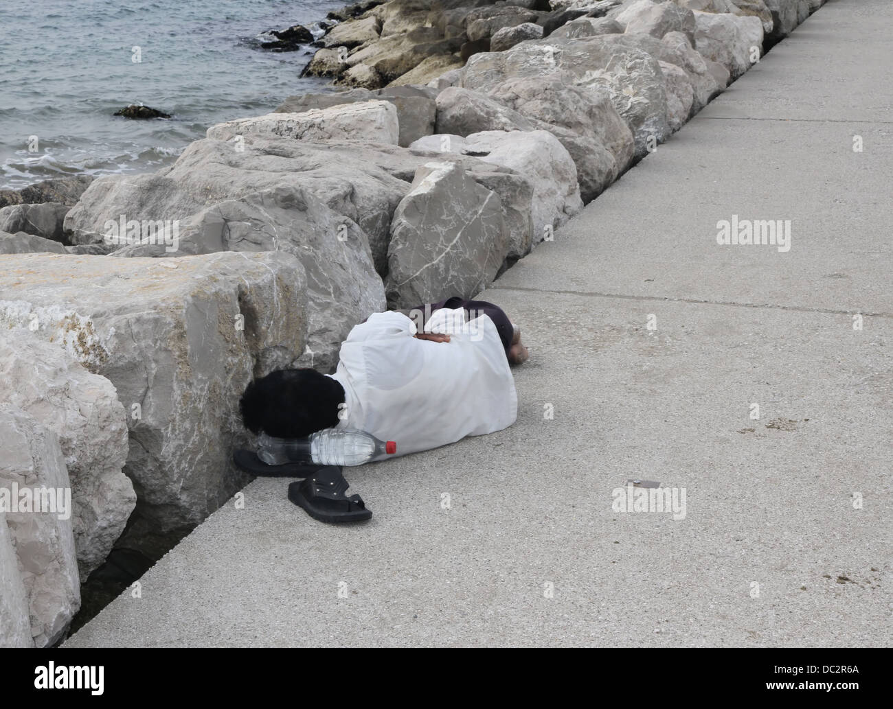 just landed kranker illegaler Einwanderer im Hafen während des Schlafens am Kai Stockfoto