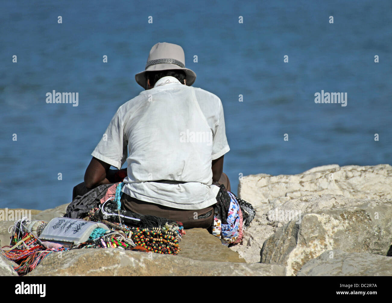 Hausierer von Halsketten und Accessoires ruht auf dem Steg am Meer im Sommer Stockfoto