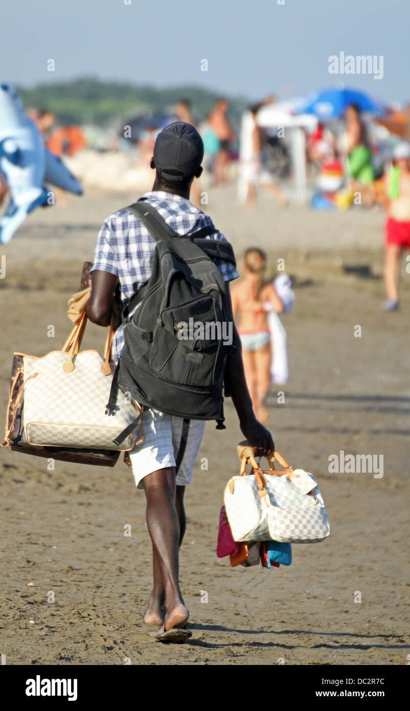 Hausierer verkauft Handtaschen und Accessoires zum Sonnenbaden am Strand im Sommer Stockfoto