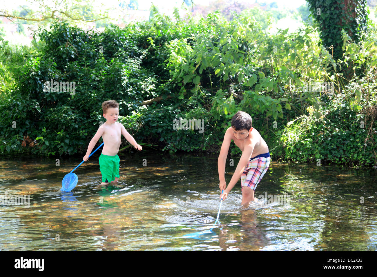 Kinder im Fluss Fischen mit Netzen. Stockfoto