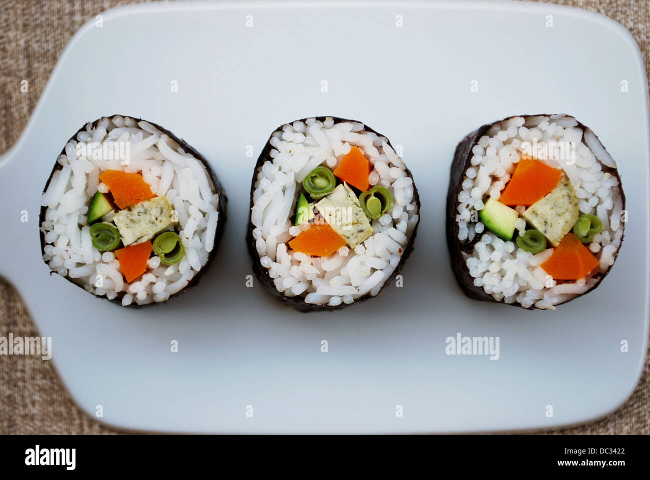 Vegetarische Maki Sushi-Rollen mit Reis, Karotten, Zucchini, grüne Bohnen, Tofu und Nori Algen in weiße Schale auf natürlichen Hintergrund Stockfoto