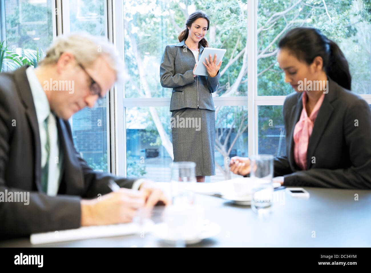 Lächelnde Frau mit digital-Tablette am Fenster im Konferenzraum Stockfoto