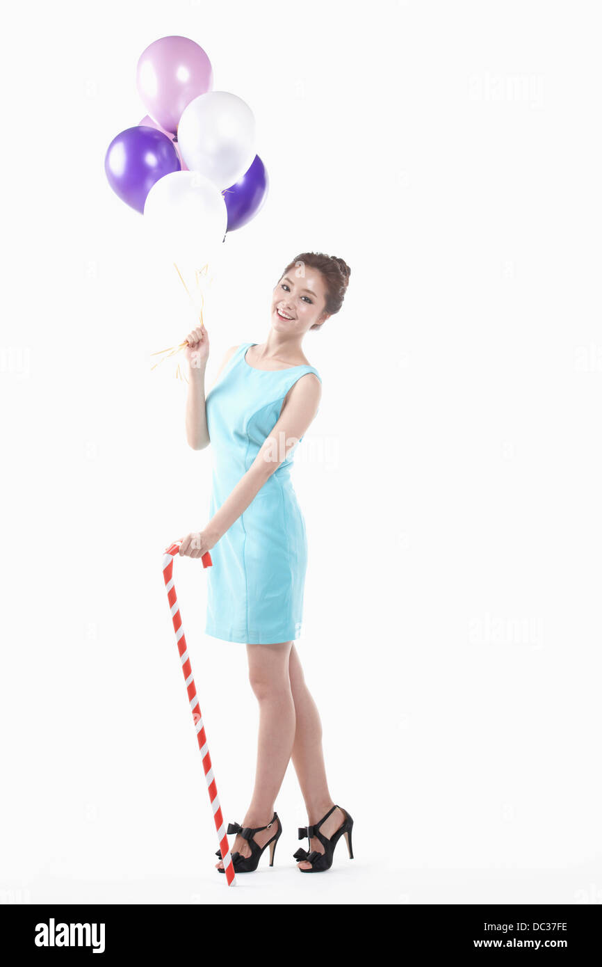 eine Dame in Minikleid posiert mit Luftballons und Rohrstock Peitsche Stockfoto