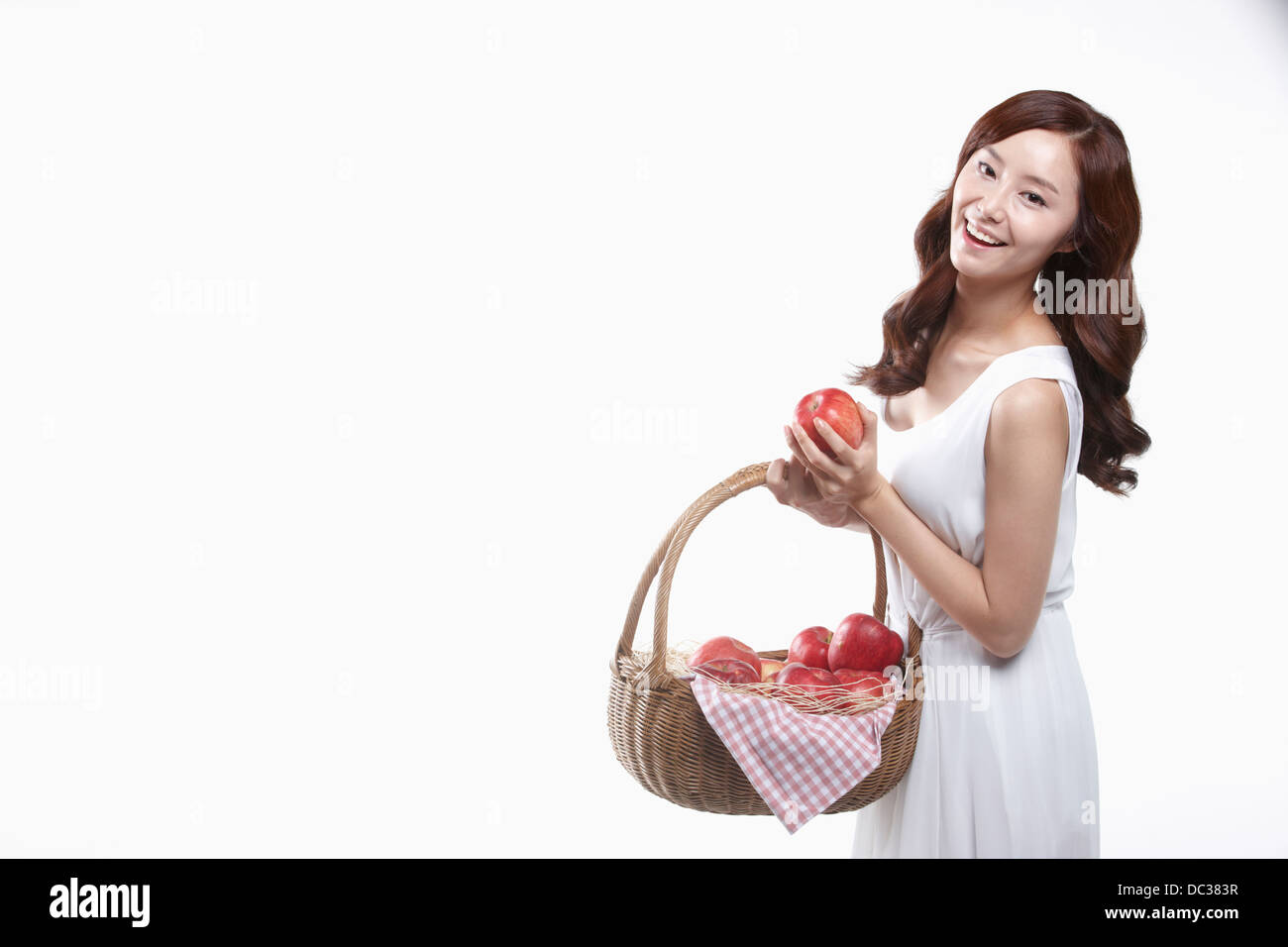 eine Dame im weißen Kleid hält einen Korb mit Äpfeln Stockfoto
