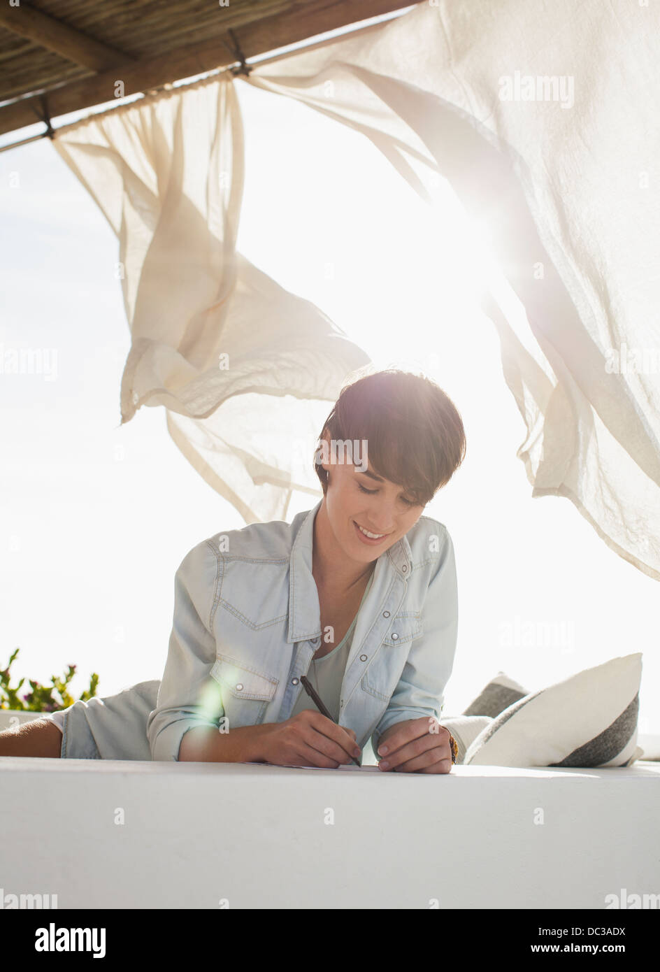 Lächelnde Frau schreiben auf sonnigen Terrasse Stockfoto