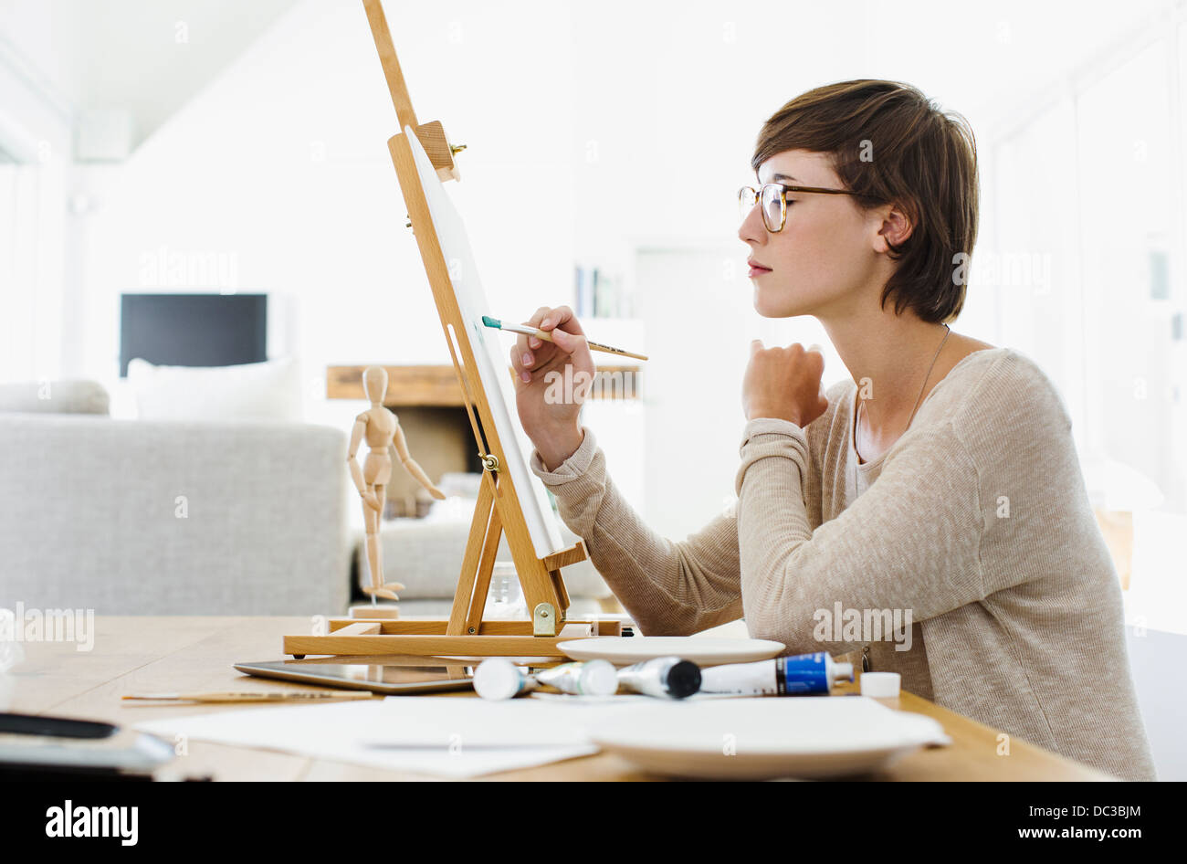 Frau malt auf Staffelei am Tisch Stockfoto