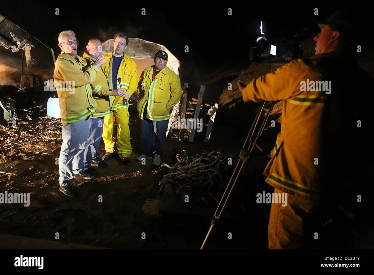 Das Verbot, CA, USA. 7. August 2013. Ein Feuer-Beamter nimmt ein Interview mit vier Fotojournalisten, die ein Haus gerettet aus der Verbrennung in Twin Pines. Die Fotojournalisten von links nach rechts sind Mike Wiesen, Steve Gentry, Shawn Kaye und Gene Blevins. Das schnell wachsende Silber Feuer explodierte über Nacht in der Nähe von Banning, Kalifornien. Das Feuer versengt 10.000 Hektar über Nacht mit Null Containment. Es gab drei Verletzungen gemeldet, darunter zwei Feuerwehrleute und ein Zivilist nach Cal Fire. Das Feuer zerstörte mehr als zwanzig Strukturen. Bildnachweis: ZUMA Press, Inc./Alamy Live-Nachrichten Stockfoto