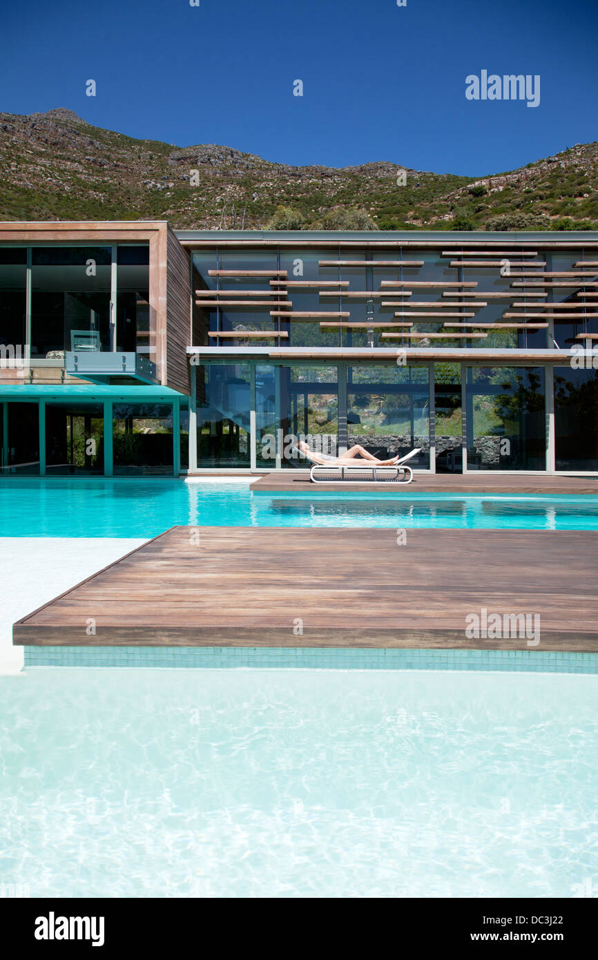 Frau zum Sonnenbaden am Pool des modernen Hauses Stockfoto