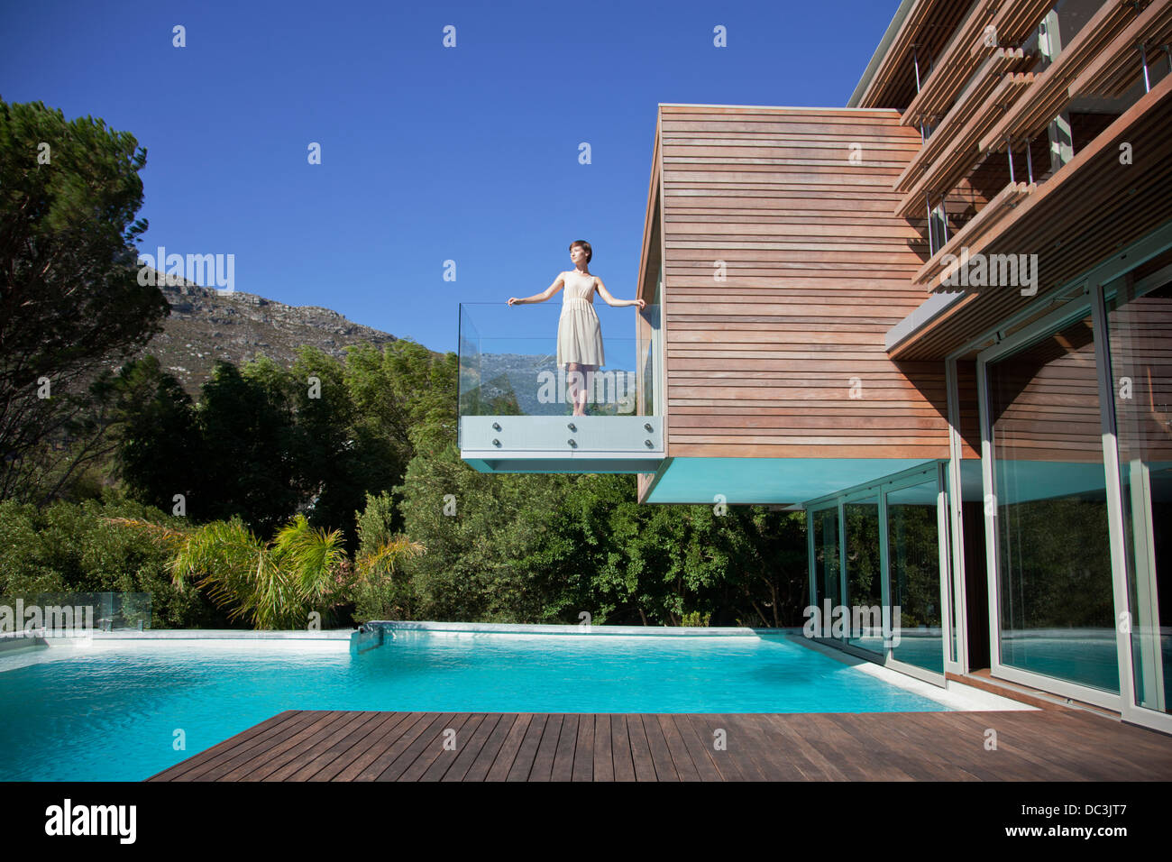 Frau stehend auf Balkon über Schwimmbad Stockfoto