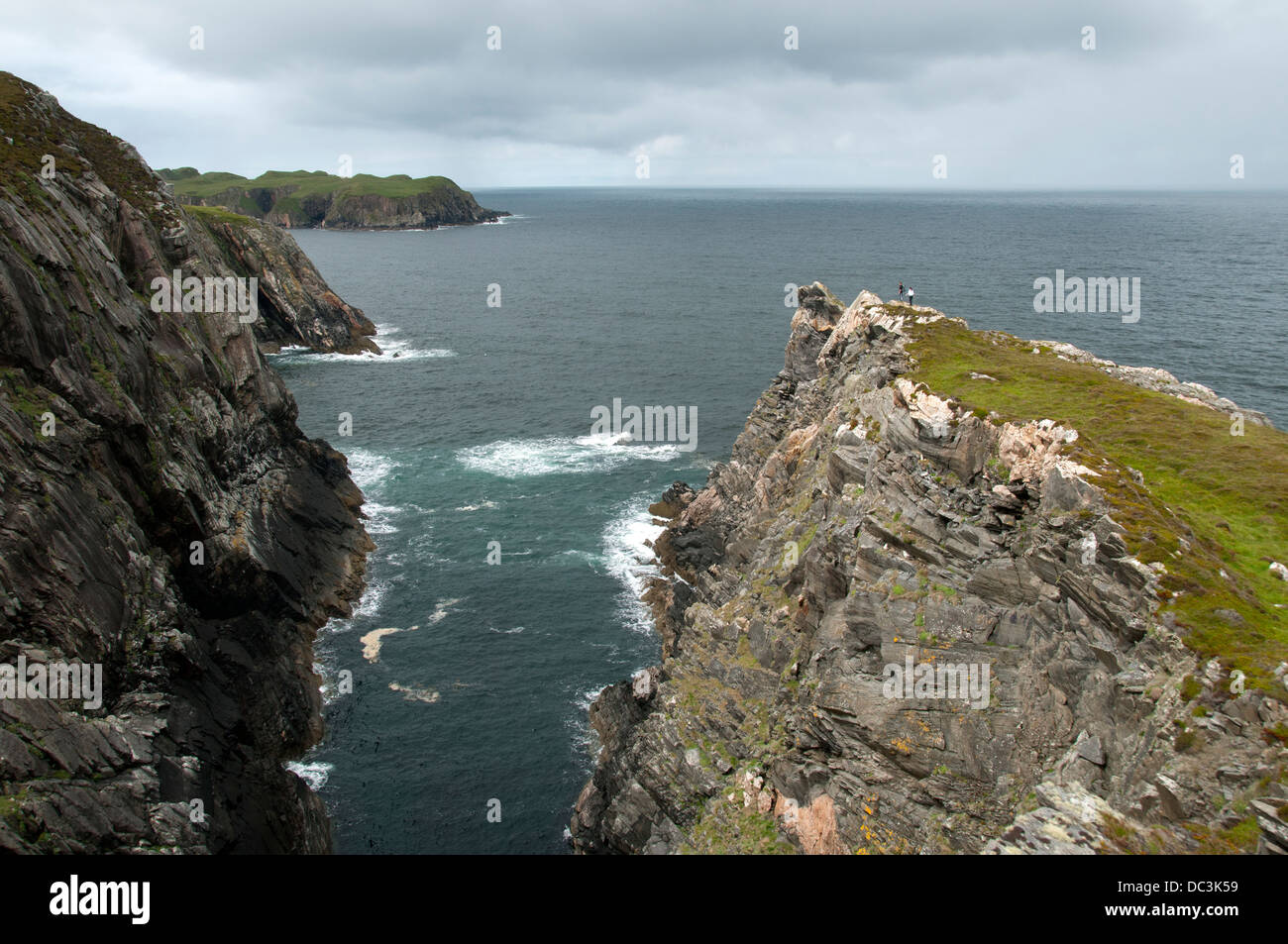 Wanderer auf einem schmalen Grat am Rande einer Geo auf Klippen in der Nähe von Skerray auf der nördlichen Küste von Sutherland, Schottland, UK. Stockfoto