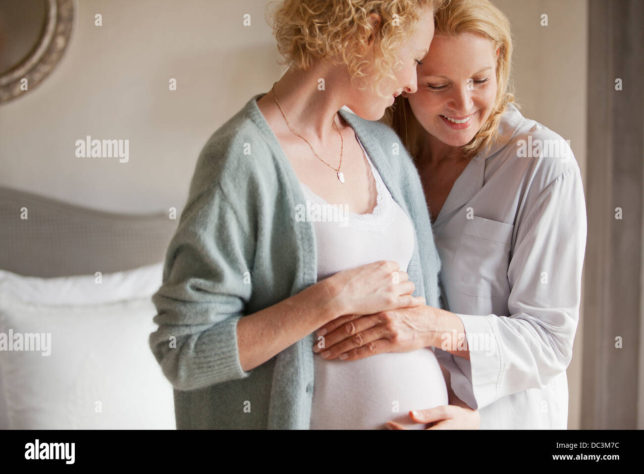 Mutter hält schwangere Tochter Magen Stockfoto