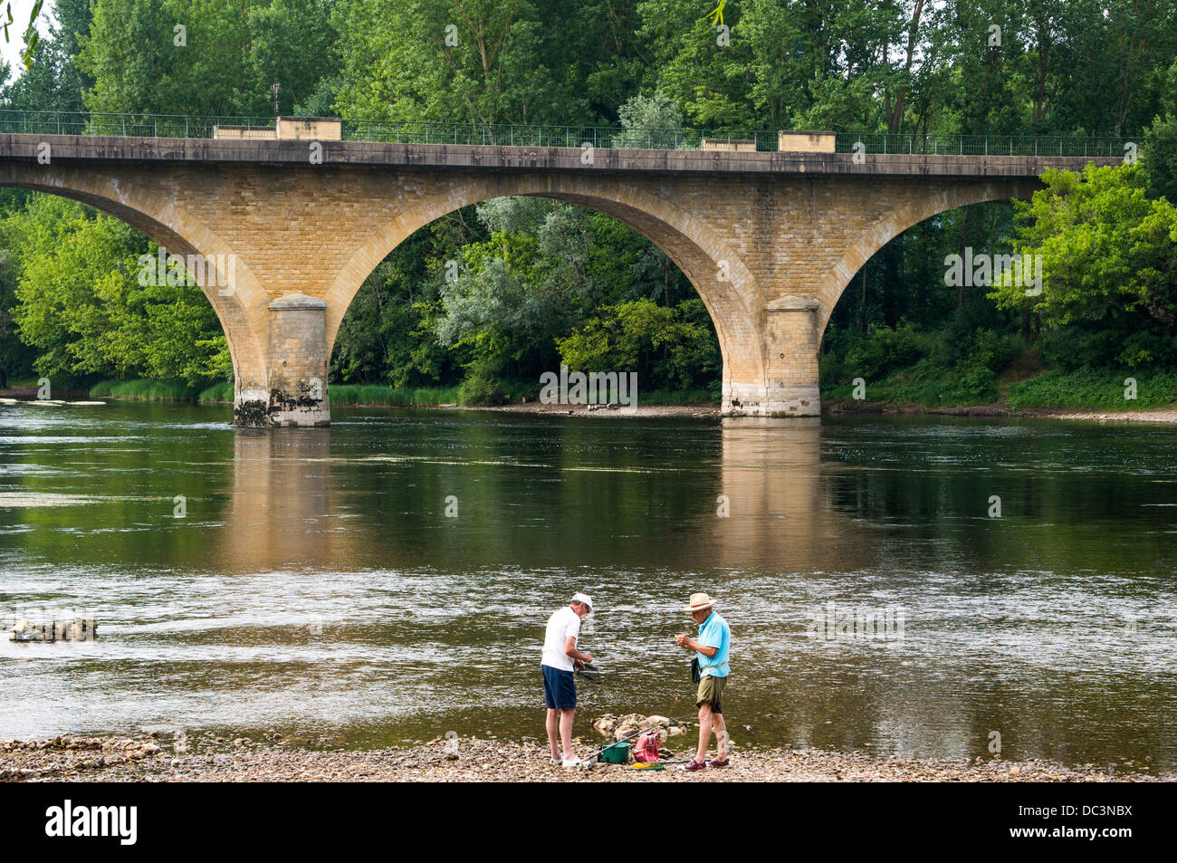 Zwei alte Männer angeln in flachen Gewässern in der Nähe der Brücke in Limeuil, liegt dort, wo die Flüsse Dordogne und Vézère, South West France. Stockfoto