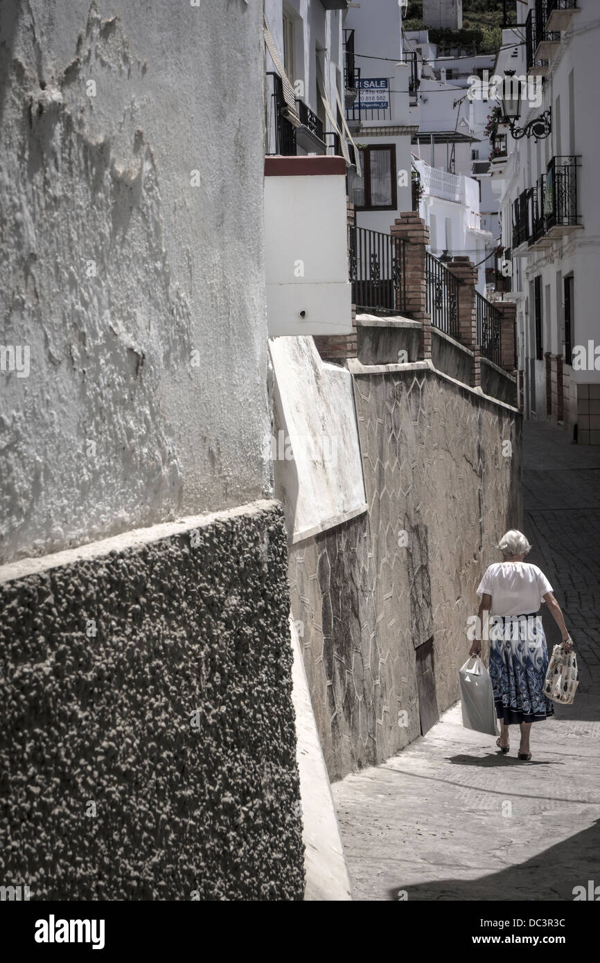 Eine Frau macht ihren Weg entlang einer der weiß getünchten Gassen von Competa in Andalusien, Südspanien. Stockfoto