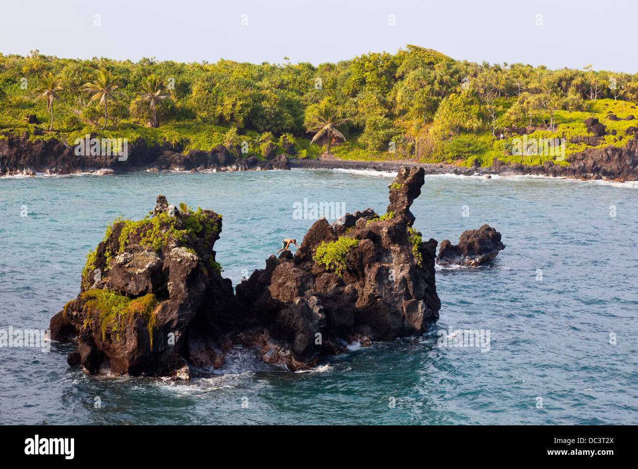 East Lava Felsen Mauis, Hawaii mit einem Mann auf den rauen Felsen klettern, um ins Wasser zu springen. Stockfoto