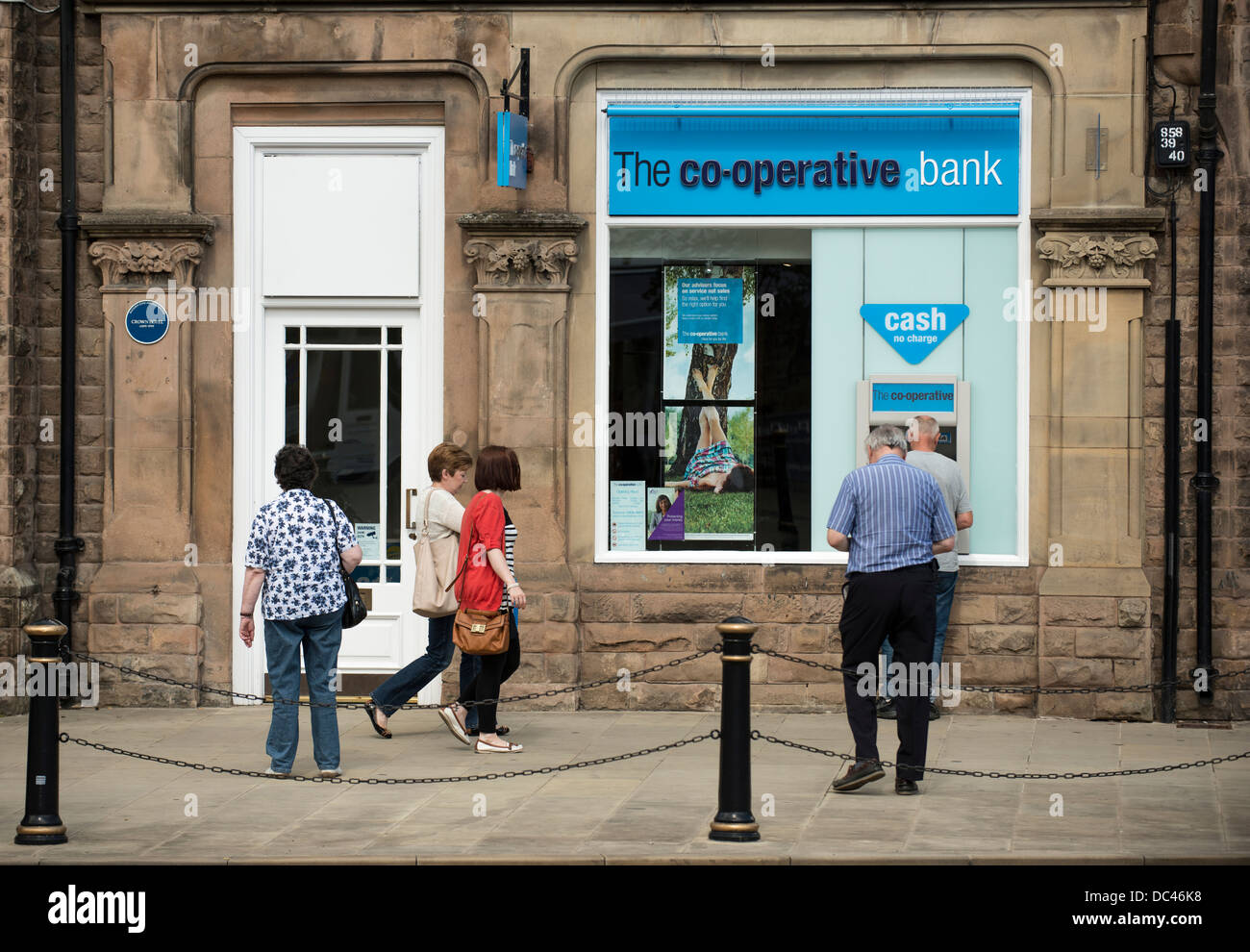 Menschen Schlange, um den Cashpoint Automaten außerhalb der genossenschaftlichen Bank in Matlock, Derbyshire nutzen Stockfoto