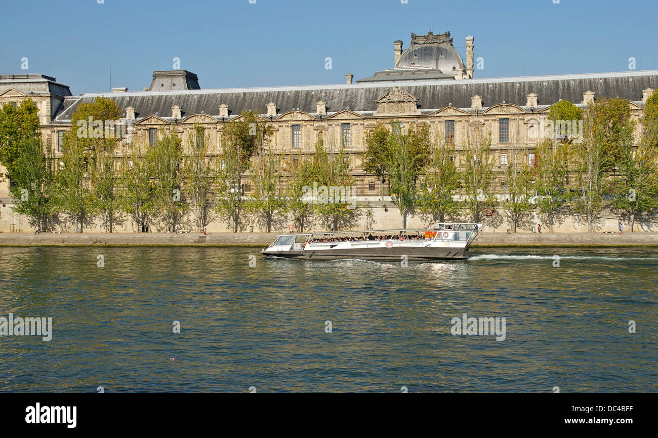 Ein Ausflugsschiff am Seineufer in Paris. Hintergrund: Quai François Mitterrand und Louvre. Stockfoto