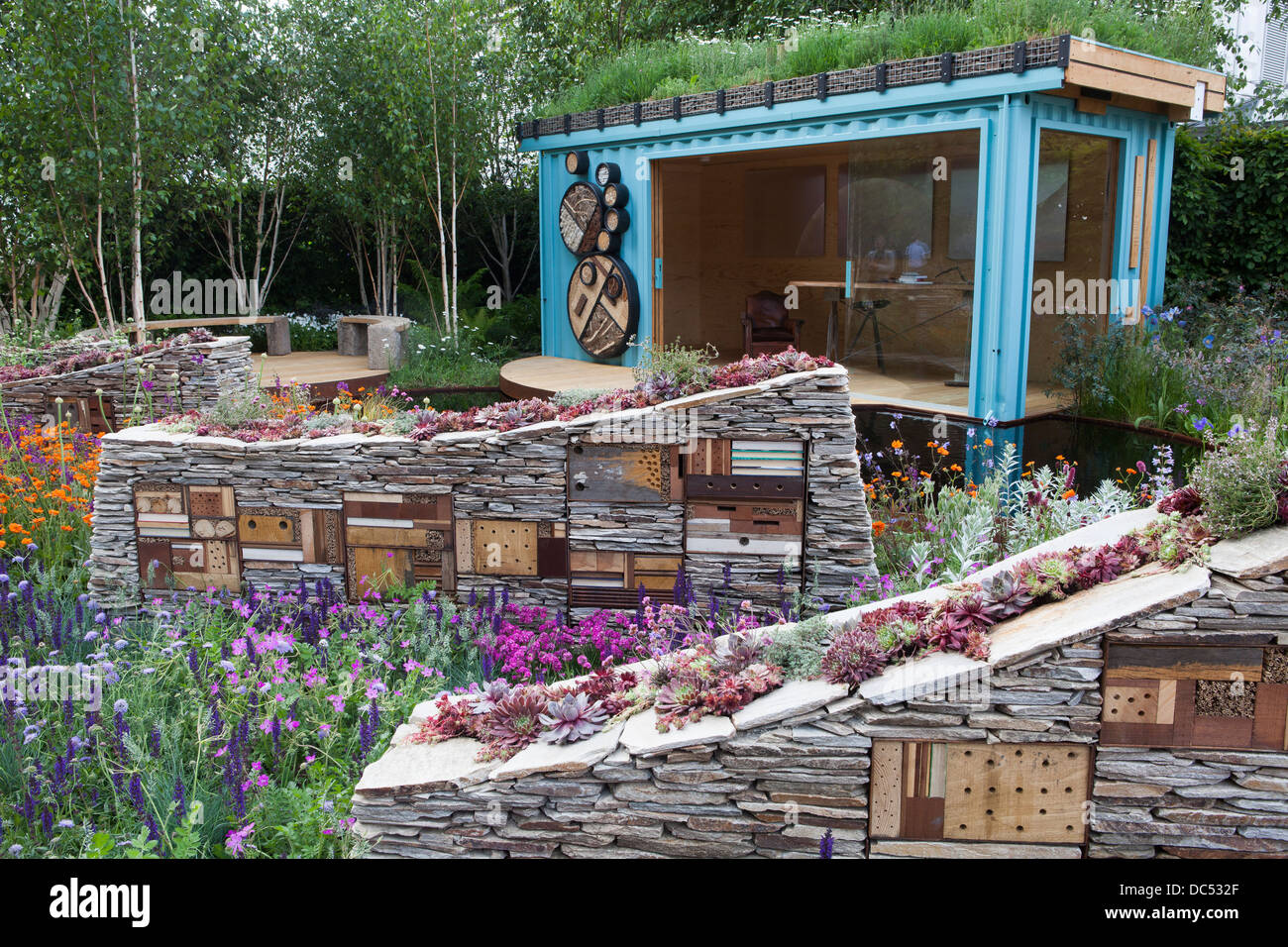 Skulpturale Trockenmauern mit Baujahr - Insektenhotels und bepflanzt mit sempervivum Stockfoto