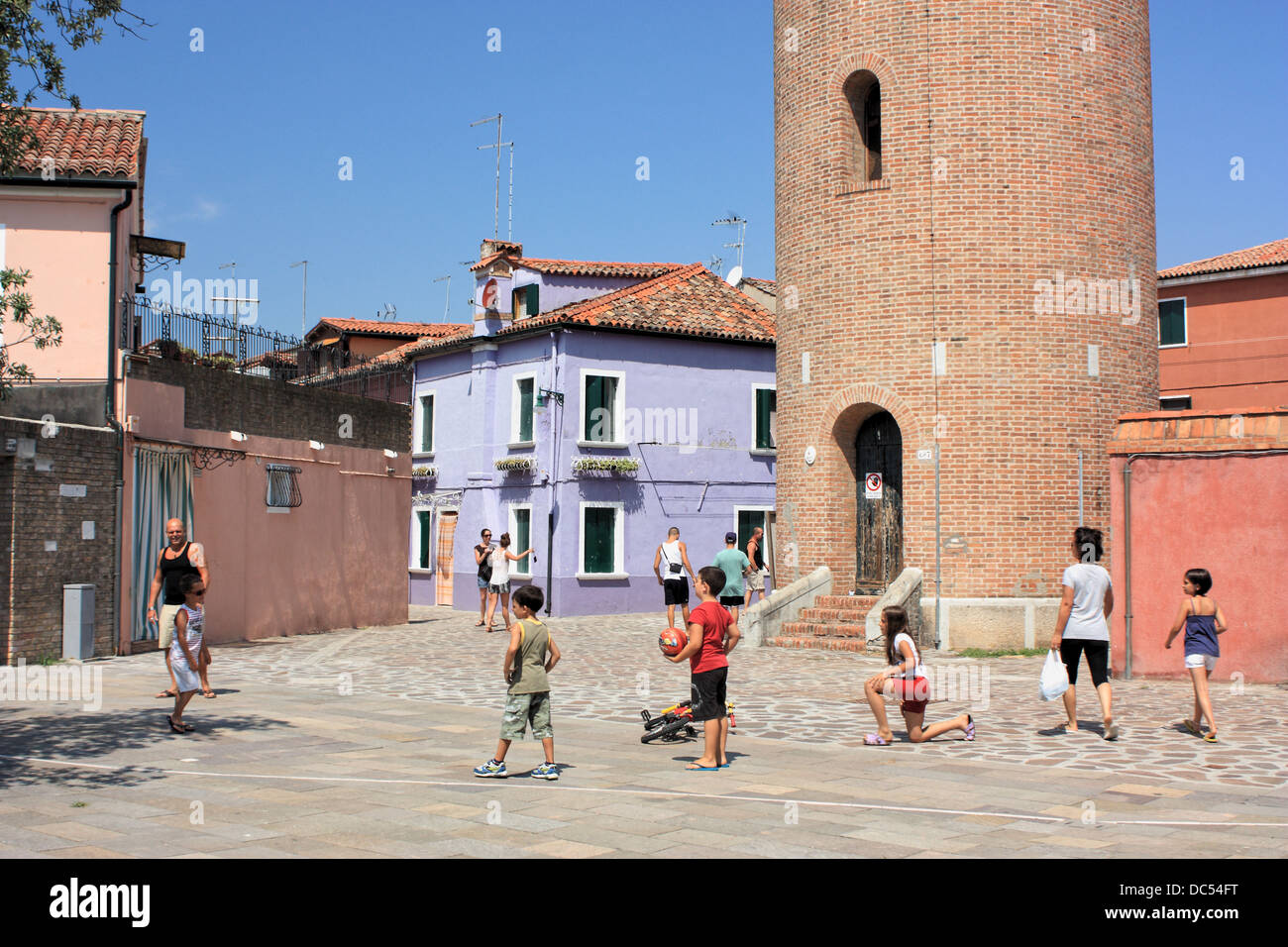 Kinder spielen auf den Straßen der Insel Burano, Isola di Burano Insel, Venedig, Italien. Wasserturm im Hintergrund. Stockfoto