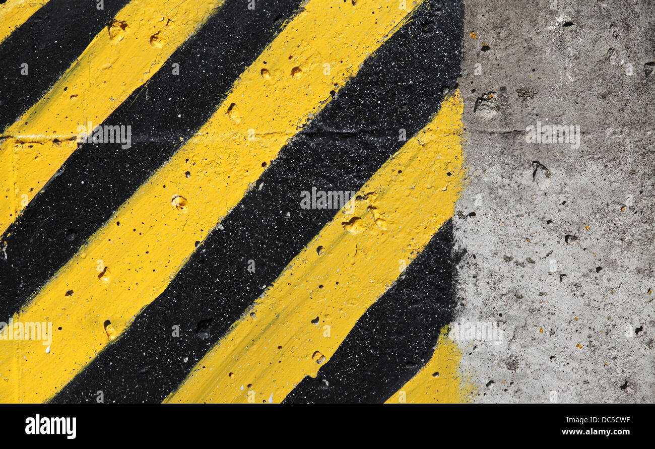 Schwarz-gelb gestreiften Vorsicht Zeichen auf graue Betonwand Stockfoto