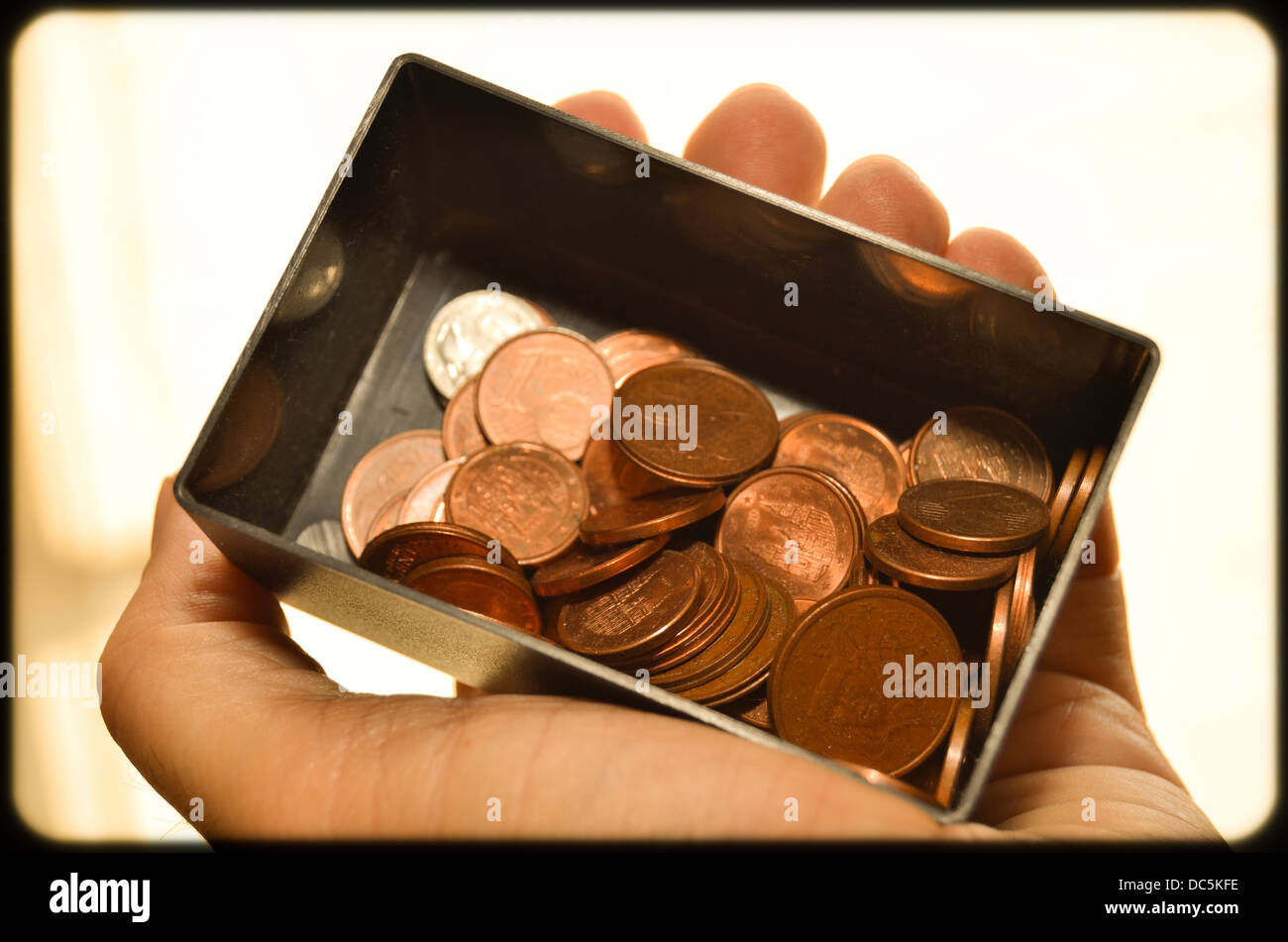 Hand hält eine Blackbox von Euro-Münzen. Stockfoto