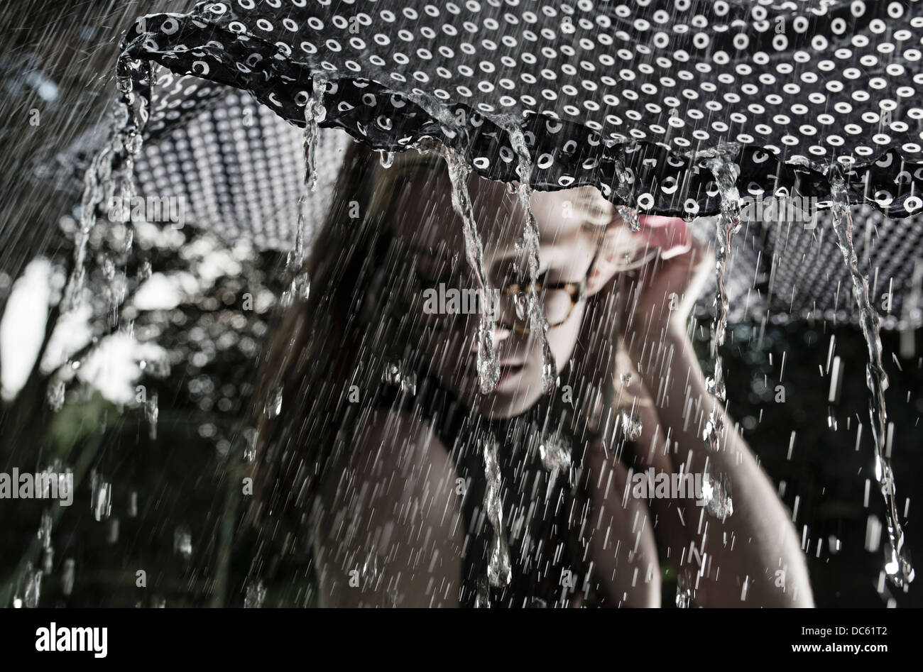 Mädchen mit Brille unter einem Regenschirm in einem Regen Sturm Stockfoto