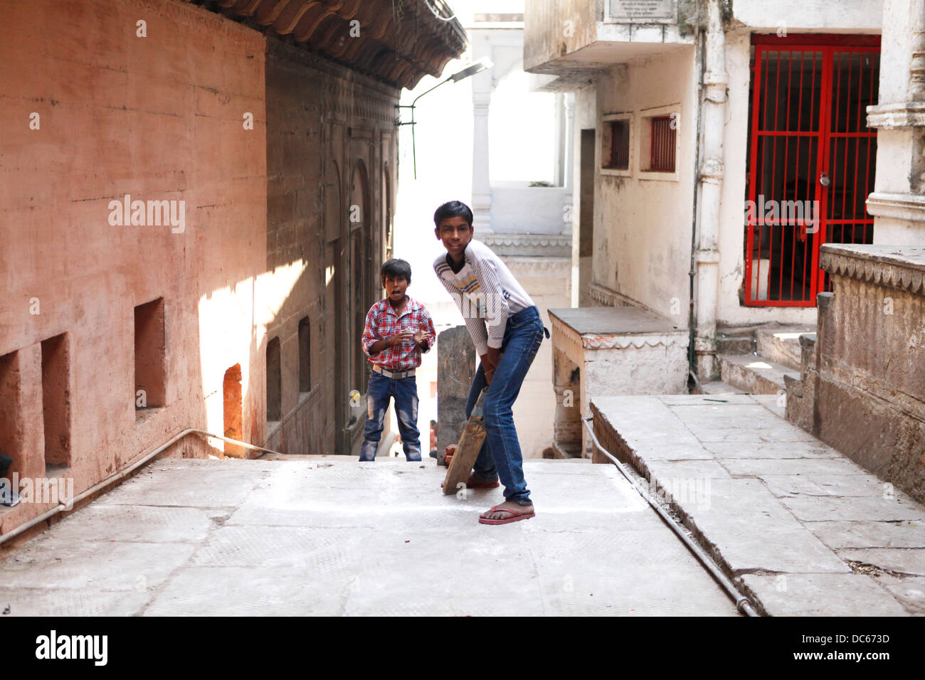 Ein paar junge Boys spielen Sie eine Partie Straße Cricket in den verwinkelten Gassen von Varanasi, Indien. Stockfoto