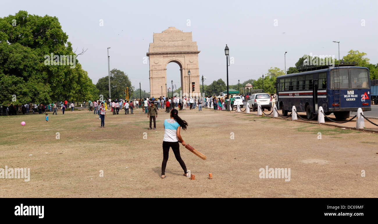 Eine Mädchen spielt Cricket im Schatten des India Gate. Ein typischer sieht Sonntag Horden von Menschen spielen auf jeder freie Stück Land. Stockfoto