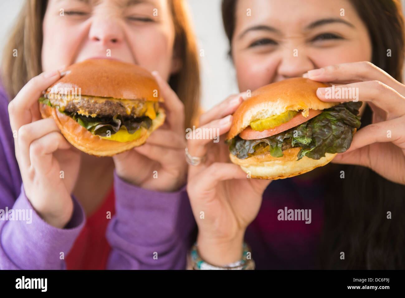 Junge Frauen, die Hamburger essen Stockfoto