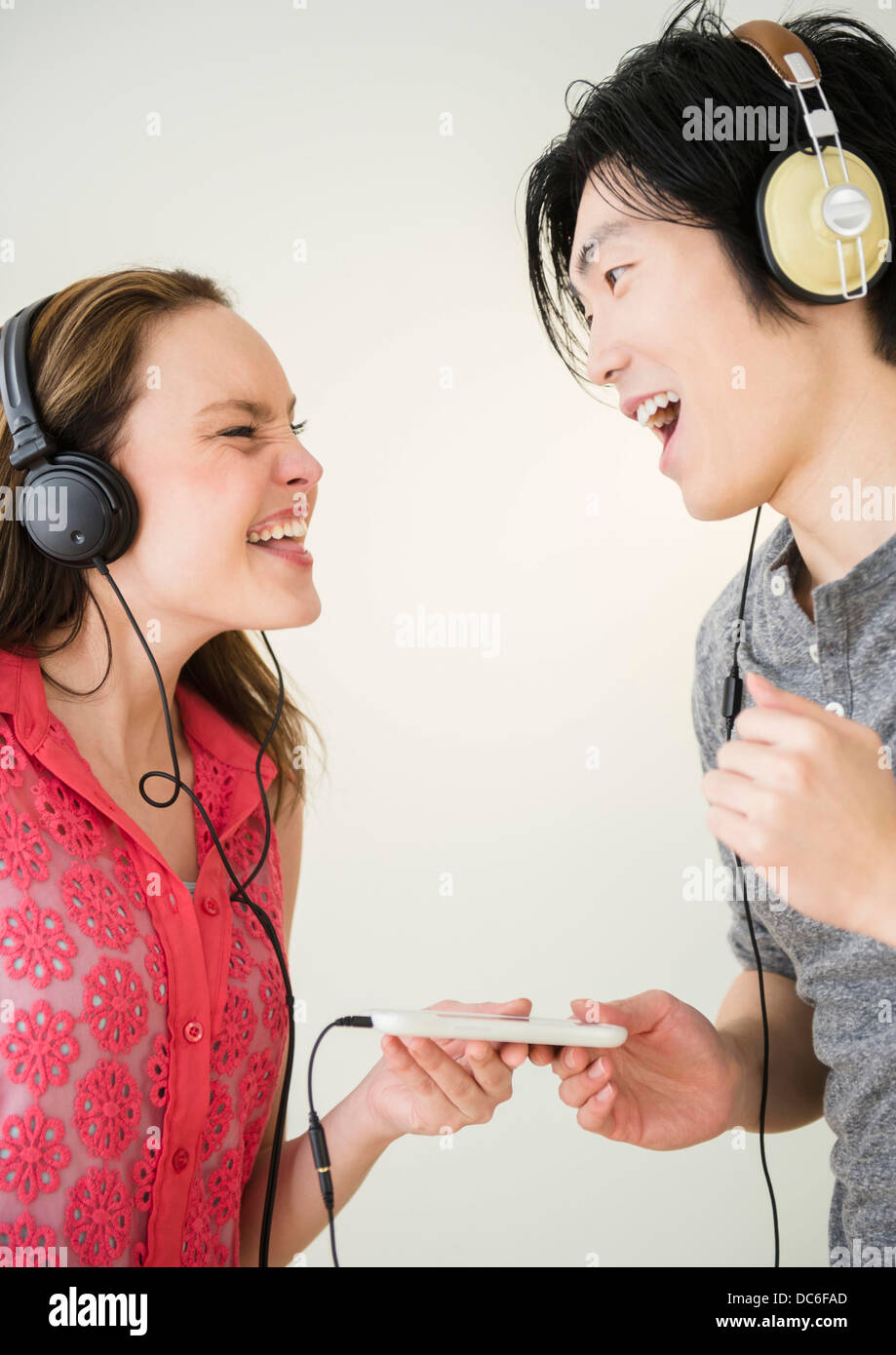 Porträt der jungen Frau und Mann anhören von Musik auf MP3-player Stockfoto