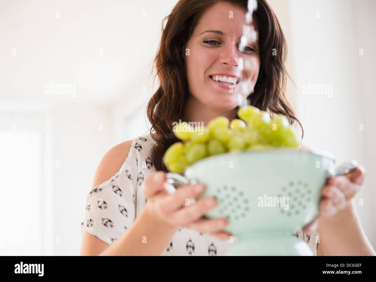 Porträt der jungen Frau, die Trauben im Sieb waschen Stockfoto