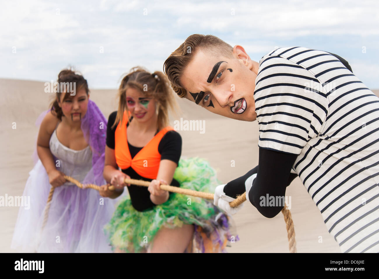 Eine junge Zirkustruppe stellen unterstützen einander im Wüstensand Stockfoto