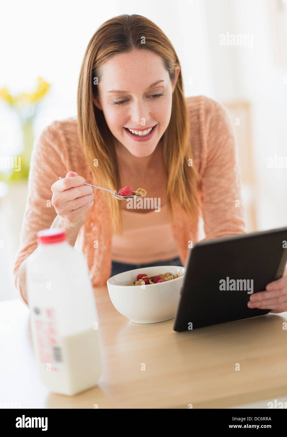 Frau essen Frühstück und Blick auf TabletPC Stockfoto