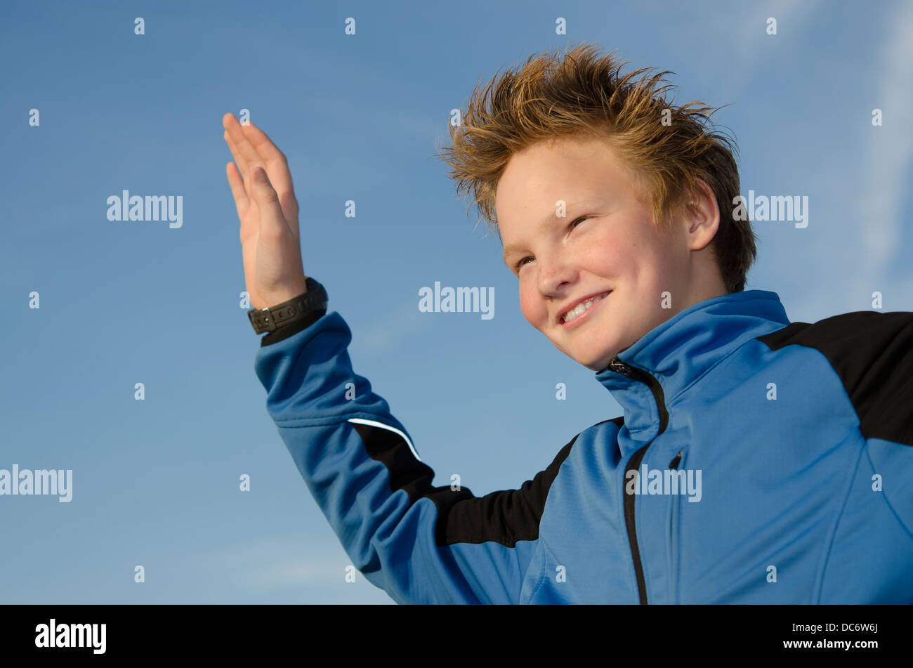 Glückliches Kind mit stacheligen Frisur freudig willkommen gegen blauen Himmel Stockfoto