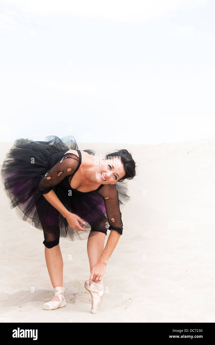 Eine Ballerina im Tutu und Pointe Schuhe auf dem Wüstensand beugt sich hinüber um zu Strecken, viel Platz für Ihre Kopie. Stockfoto
