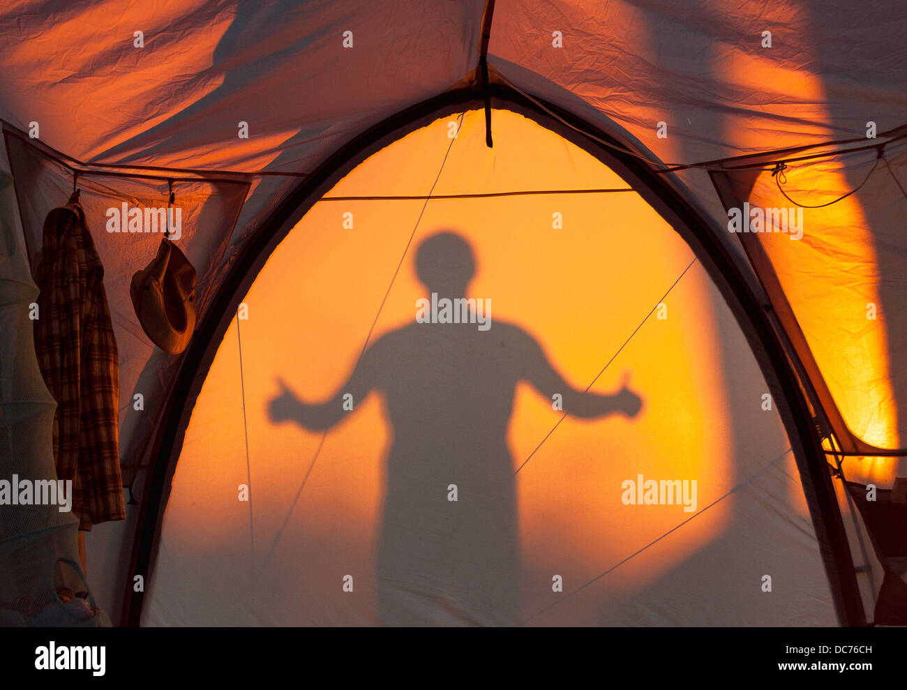 Silhouette des Mannes gestikulieren "OK" spiegelt sich in einem Zelt Stockfoto