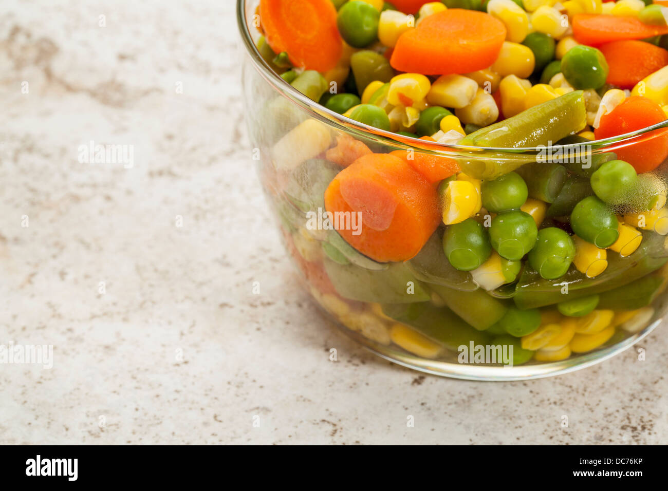 Mischung aus gekochtem Gemüse (Karotten, grüne Erbsen, Bohnen, Mais) in eine Glasschüssel Stockfoto