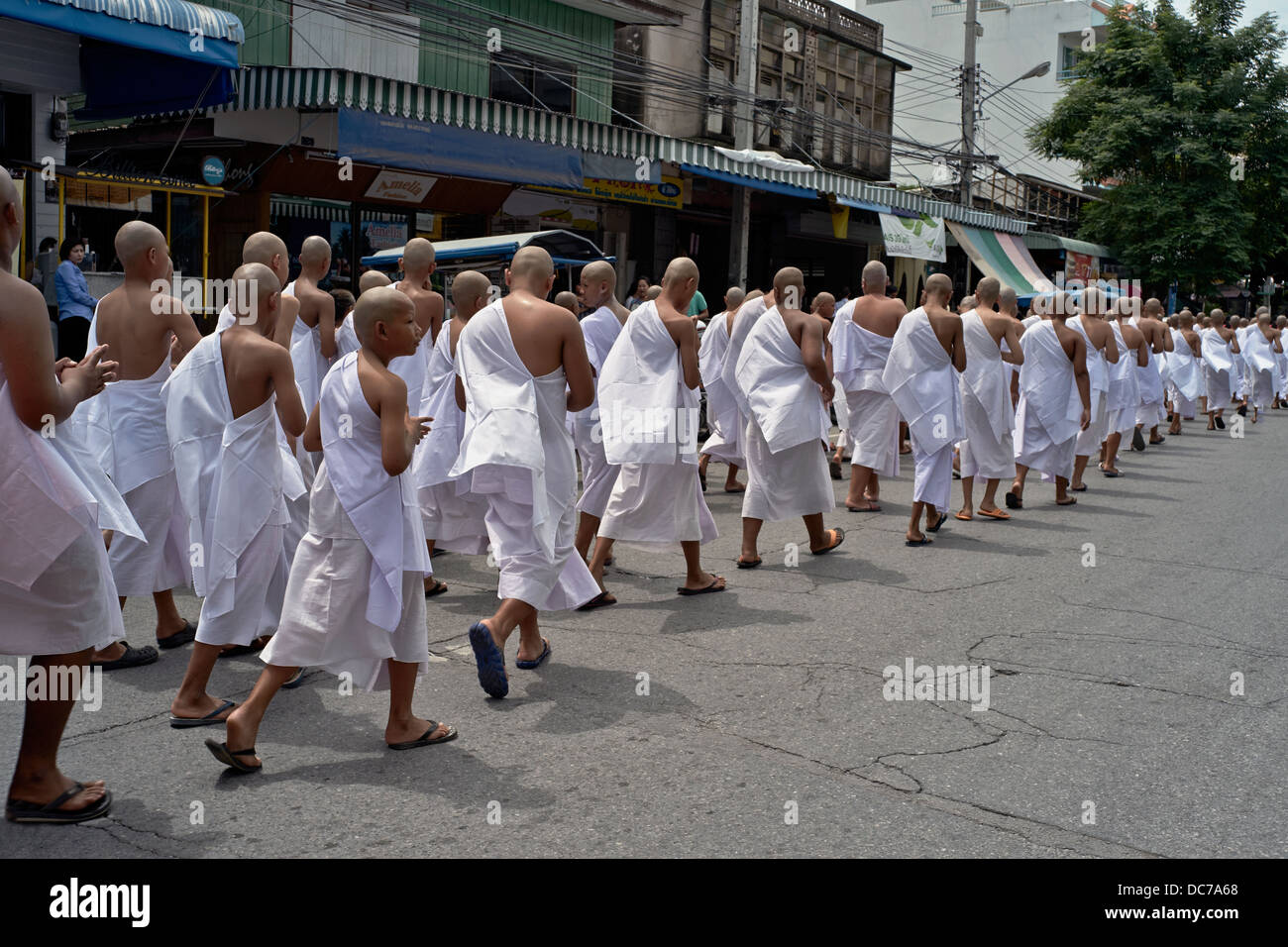 Thailändische Jungenmönche. Buddhistische Novizenmönche, die auf dem Weg zu ihrer Weihefeier durch die Straße paradieren. Thailand S. E. Asien. Stockfoto