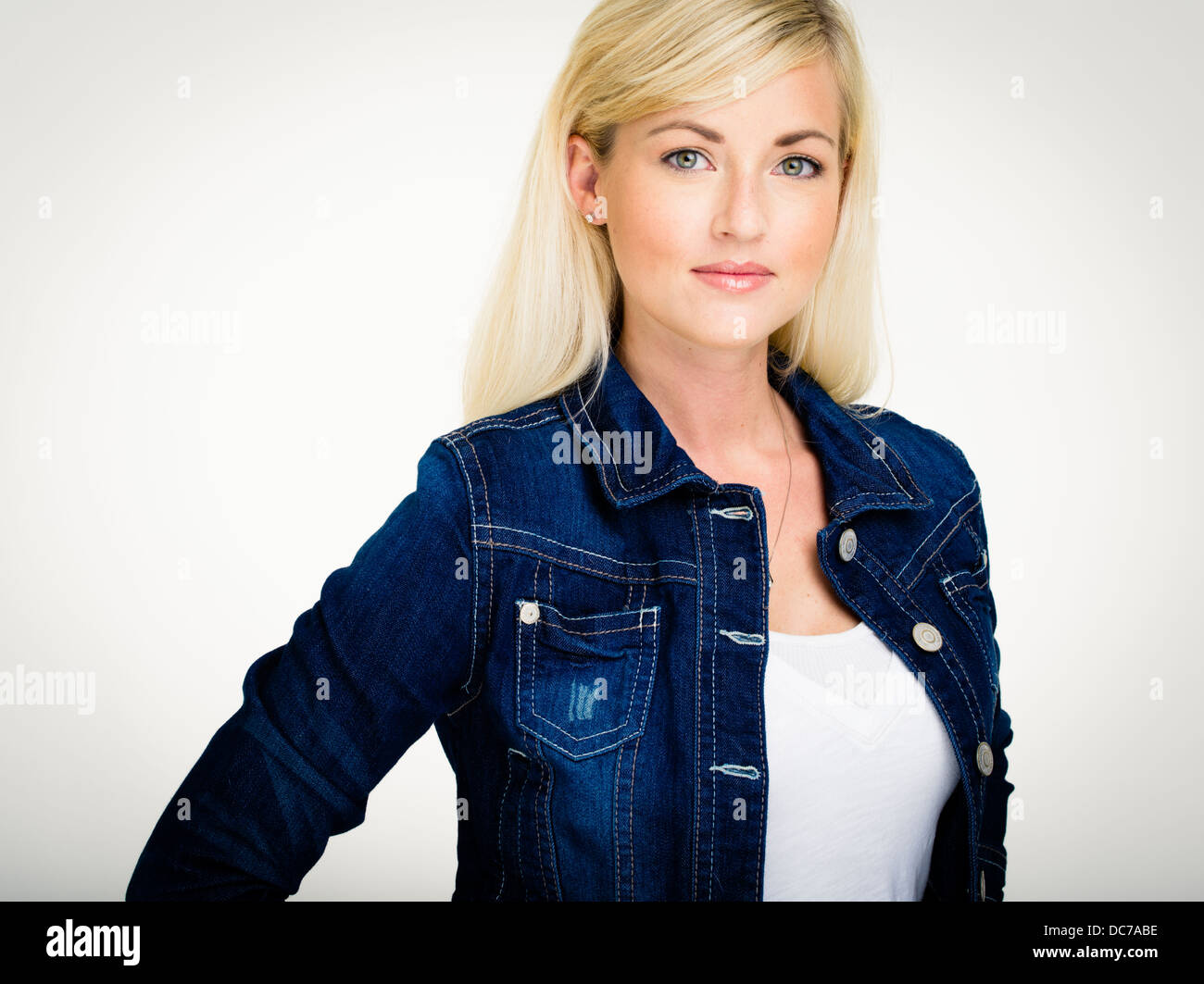 Schöne blonde kaukasischen Frau in ihren Zwanzigern tragen indigo blau Denim Jacke und weiße t-shrit Stockfoto