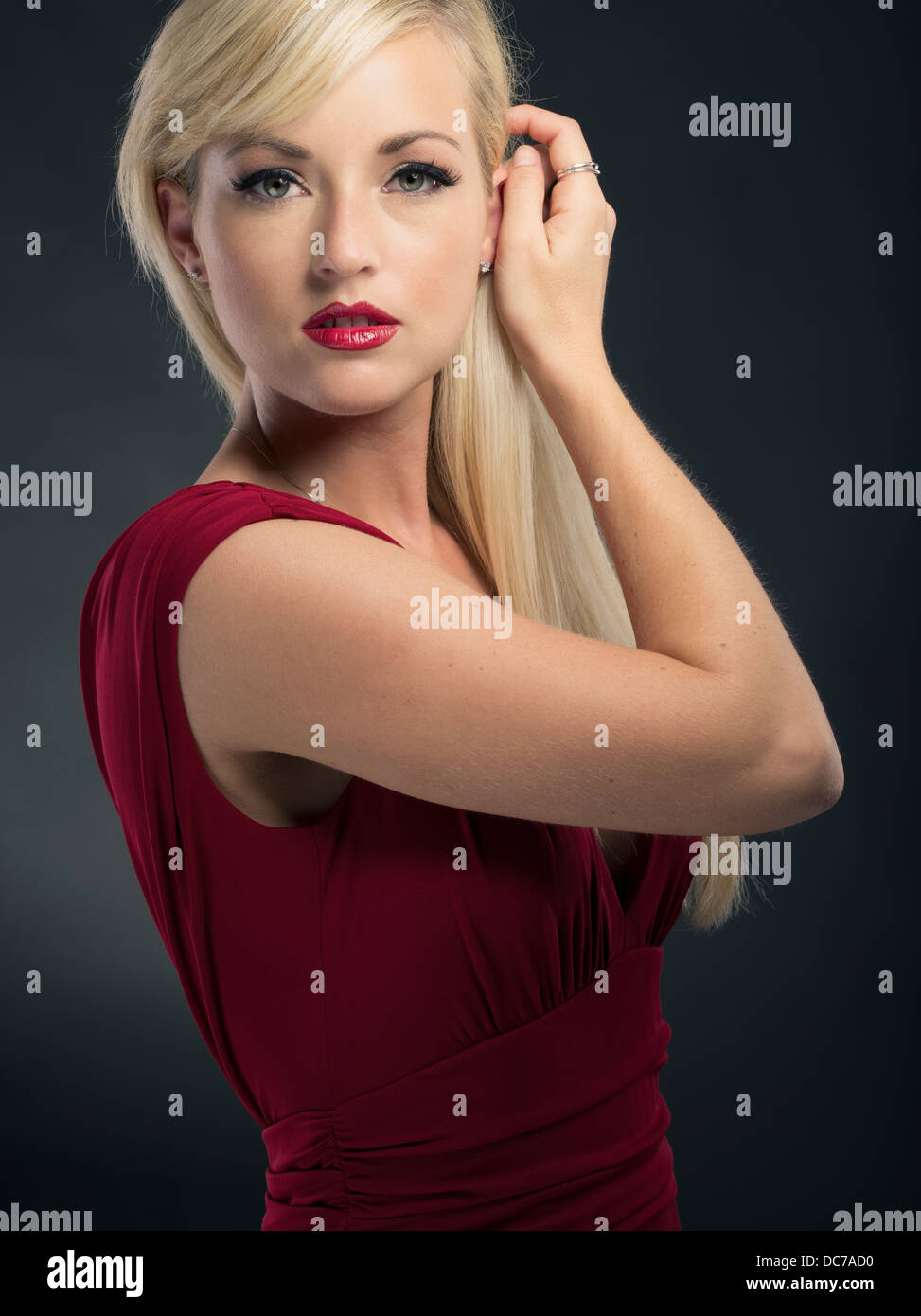 Schöne blonde kaukasischen Frau in ihren Zwanzigern tief roten Kleid formelle Kleid tragen Stockfoto